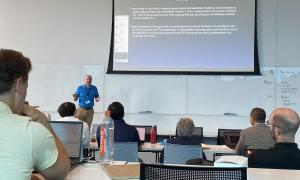Meeting Room:  Speakers in front of attendees, slides behind speakers 
